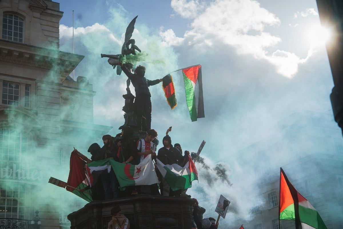Palestine youths on statue with flare